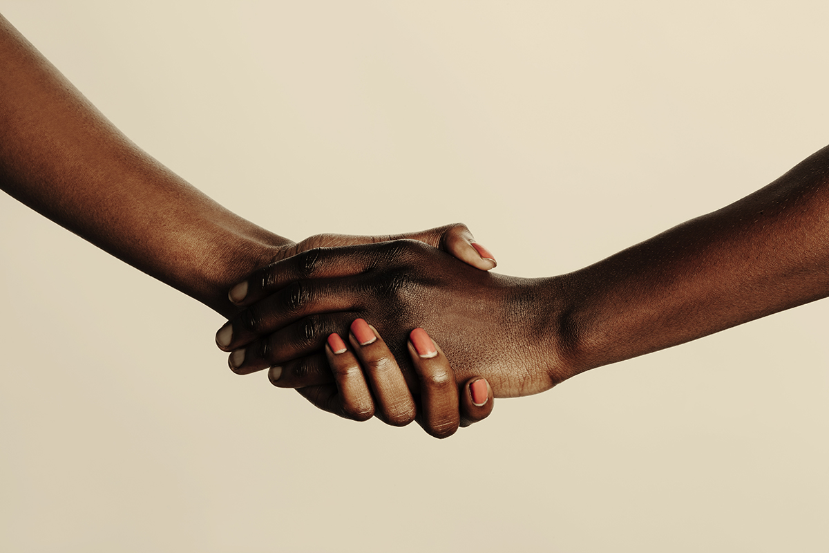 Two clasped hands against a beige background