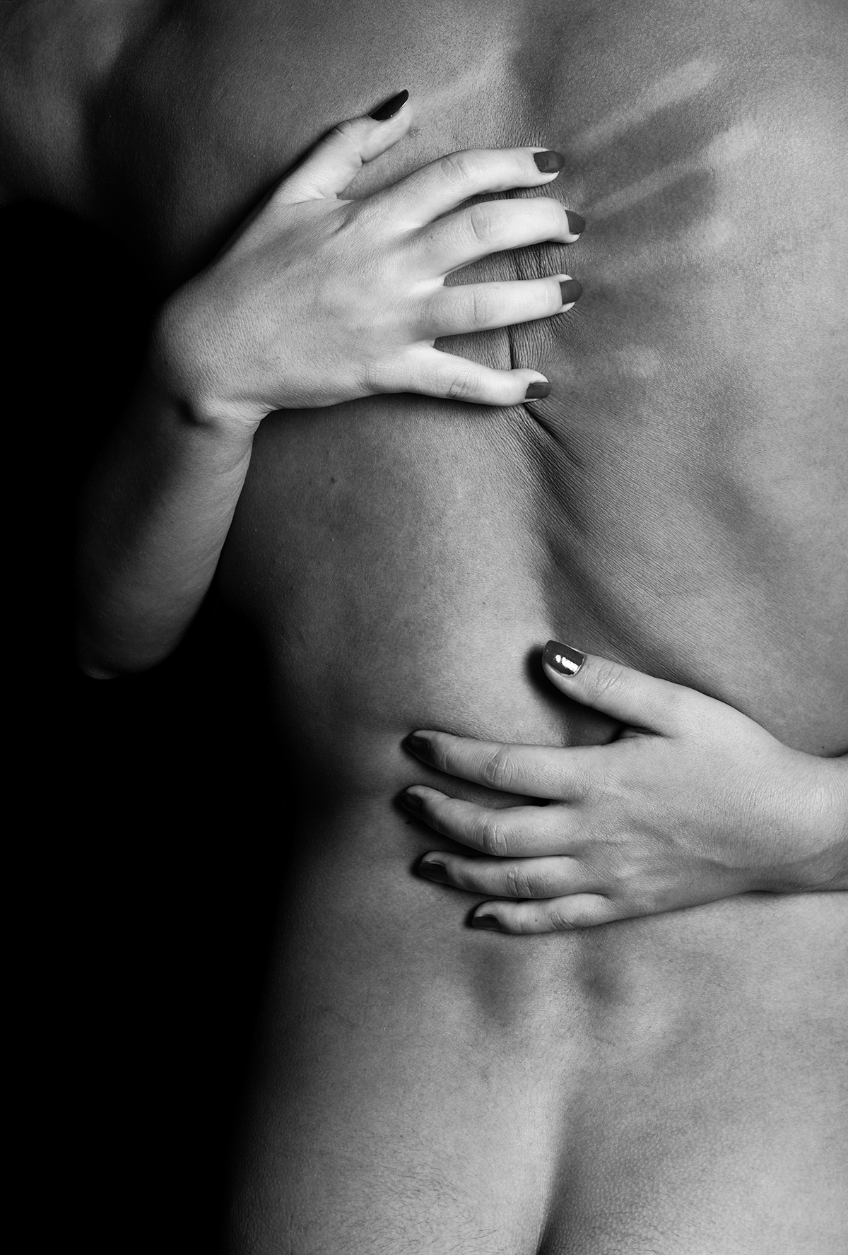 A black and white image of female hands scratching a naked man's back