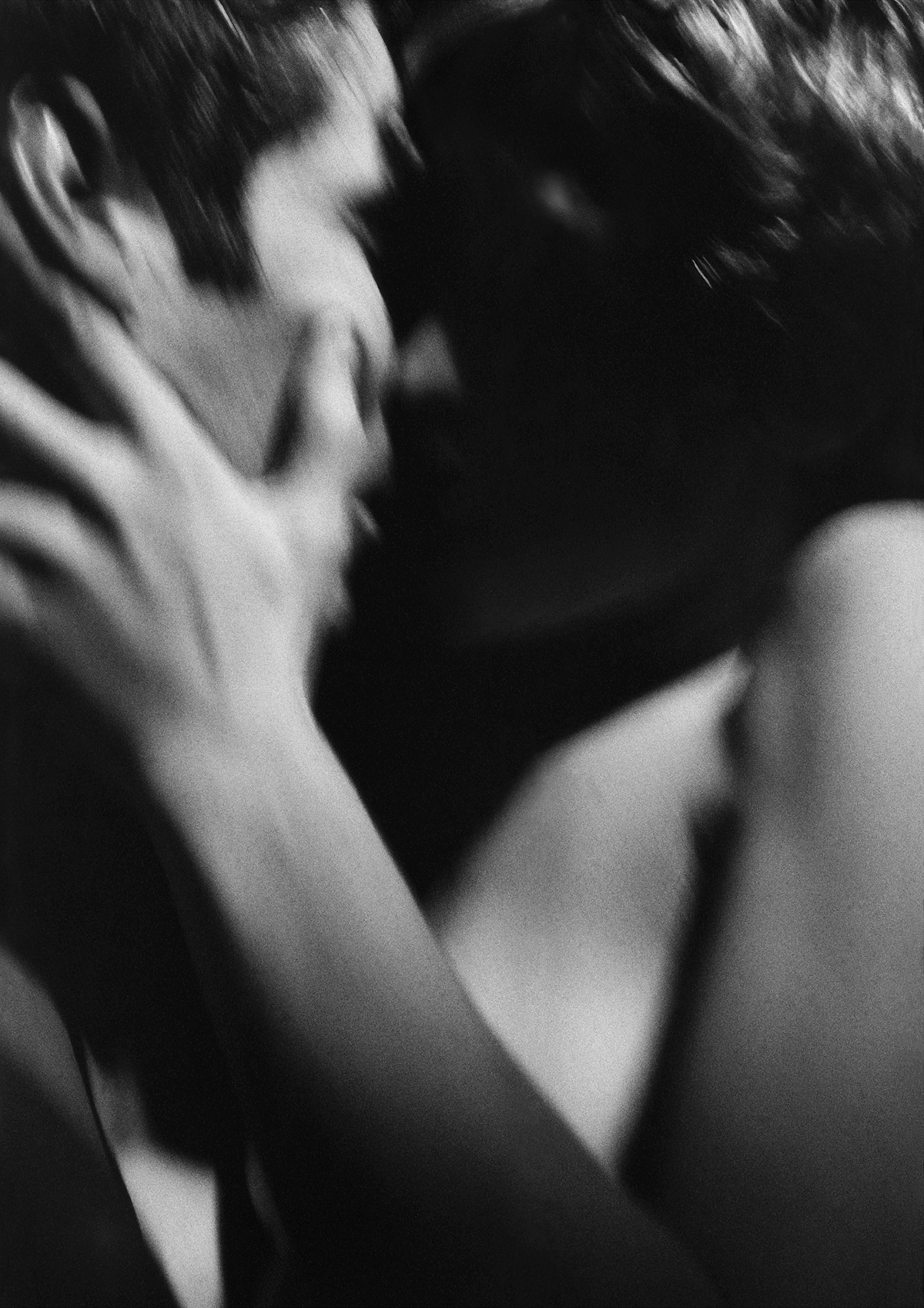 A blurry black and white photo of a couple kissing