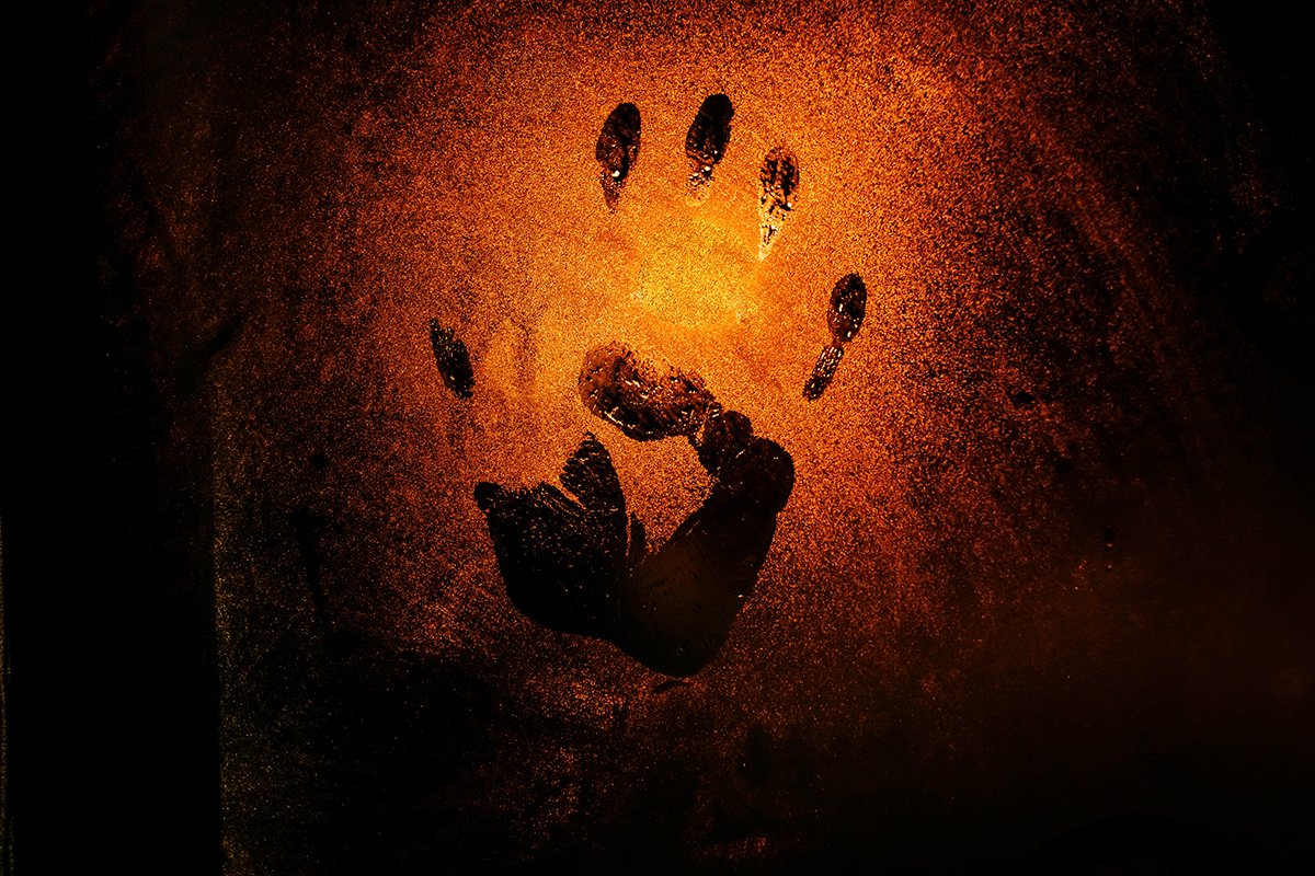 A handprint on glass, illuminated by a warm light